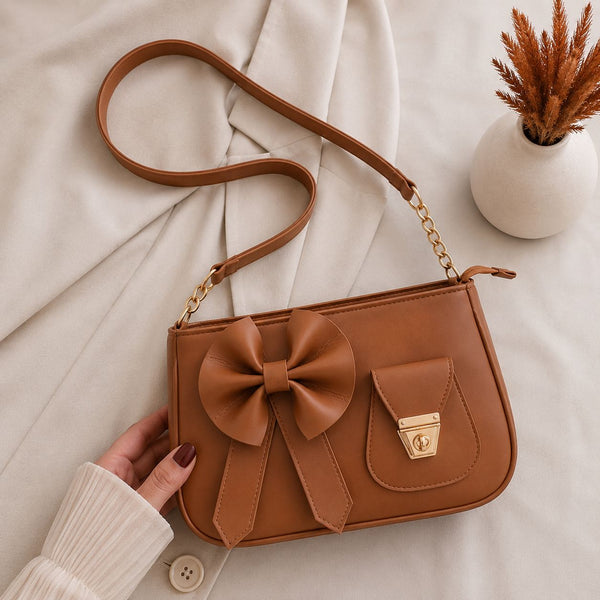 Artisanal classic tan brown shoulder creation resting alongside a minimalist ceramic vase with dried grass accents.