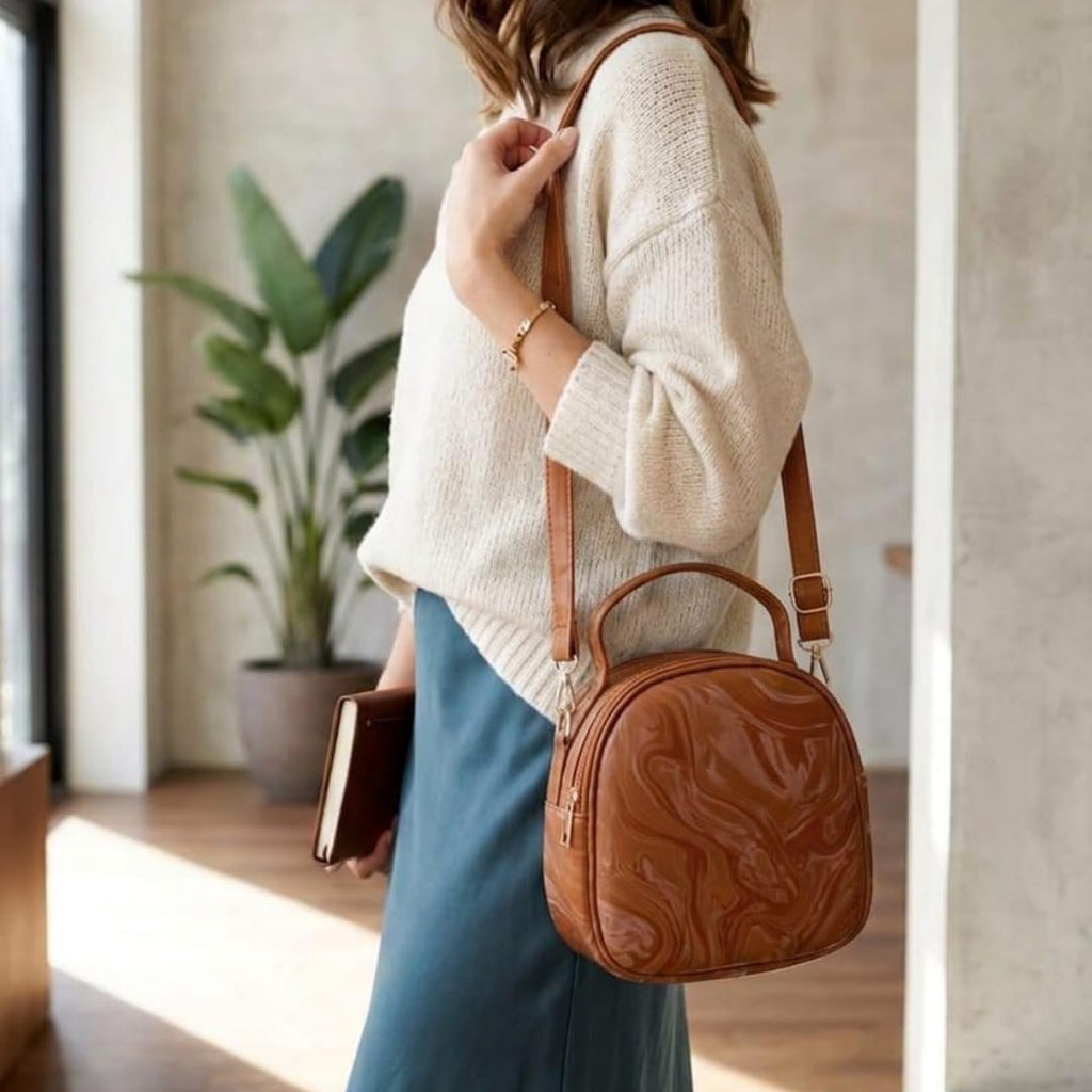 Elegant monochromatic classic tan brown version of the trend in aesthetics round silhouette displaying its structured rigid top-handle loop.