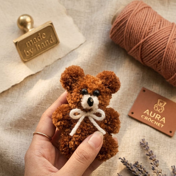 Front showcase of the Range Studio artisanal teddy pom charm in earthy brown featuring a fluffy cloud-soft texture and custom floral accents.