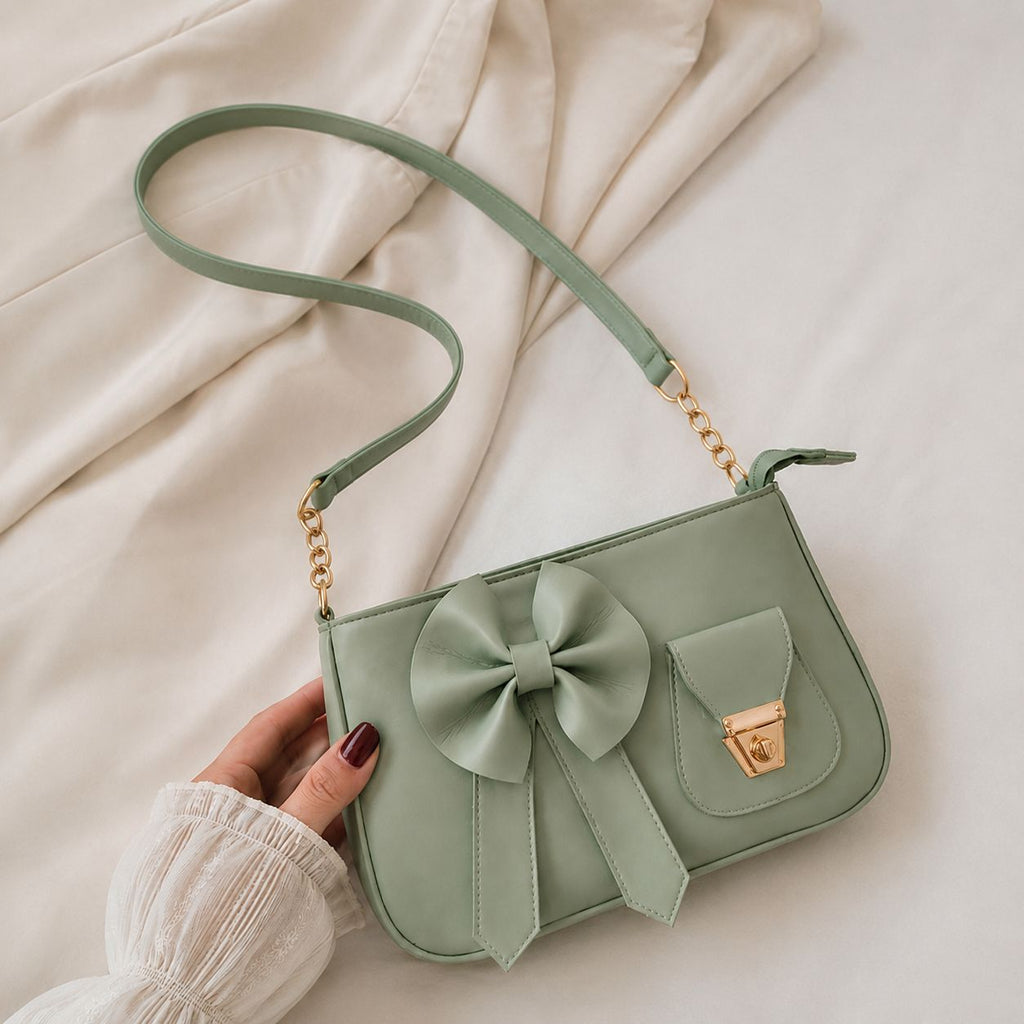 Front display of the Range Studio coquette bow shoulder silhouette in sage mint green featuring a prominent matching leather bow and a golden metallic twist lock enclosure.