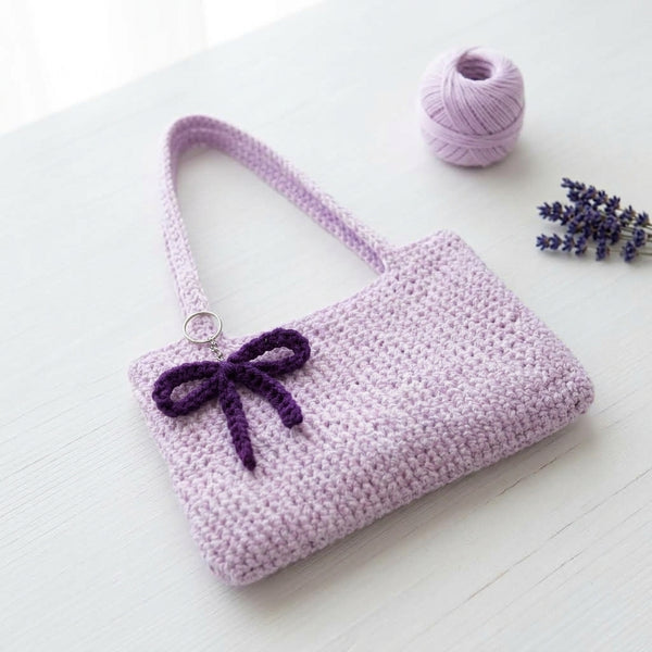 Front display of the Range Studio Ribbon & Bow Petite Tote in elegant purple featuring soft hand-woven textures and contrasting ribbon details.