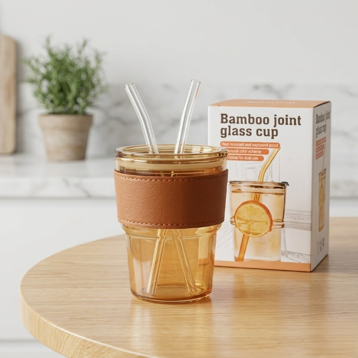 Front display of the Range Studio bamboo joint amber glass cup showing the leather sleeve, two glass straws, and branded product box package.