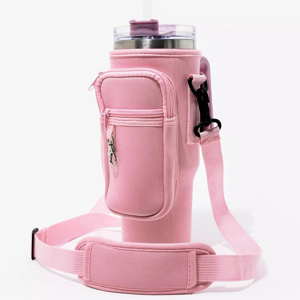 Side profile view of the Blush Tea Pink Range Studio insulated tumbler carrier sleeve showing the zipper utility pocket and adjustable shoulder strap attached to a travel mug .