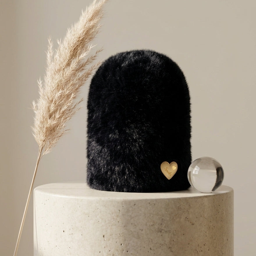 Front angle view of the Onyx Black variant Range Studio plush rabbit wool beanie styled on a modern stone pillar next to a clear glass orb.