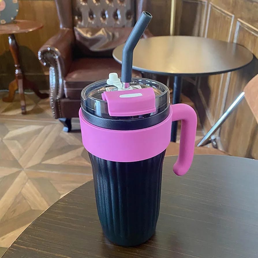 The Onyx and Magenta variant of the Range Studio Ribbed Travel Tumbler displayed elegantly on a dark coffee table backdrop.