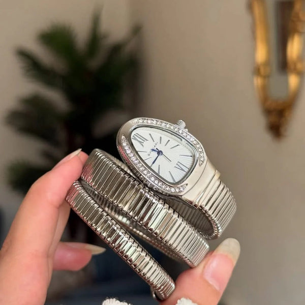 A woman holding the Classic Silver variant Range Studio snake bracelet wrap watch to highlight its flexible double-coil wristband structure.