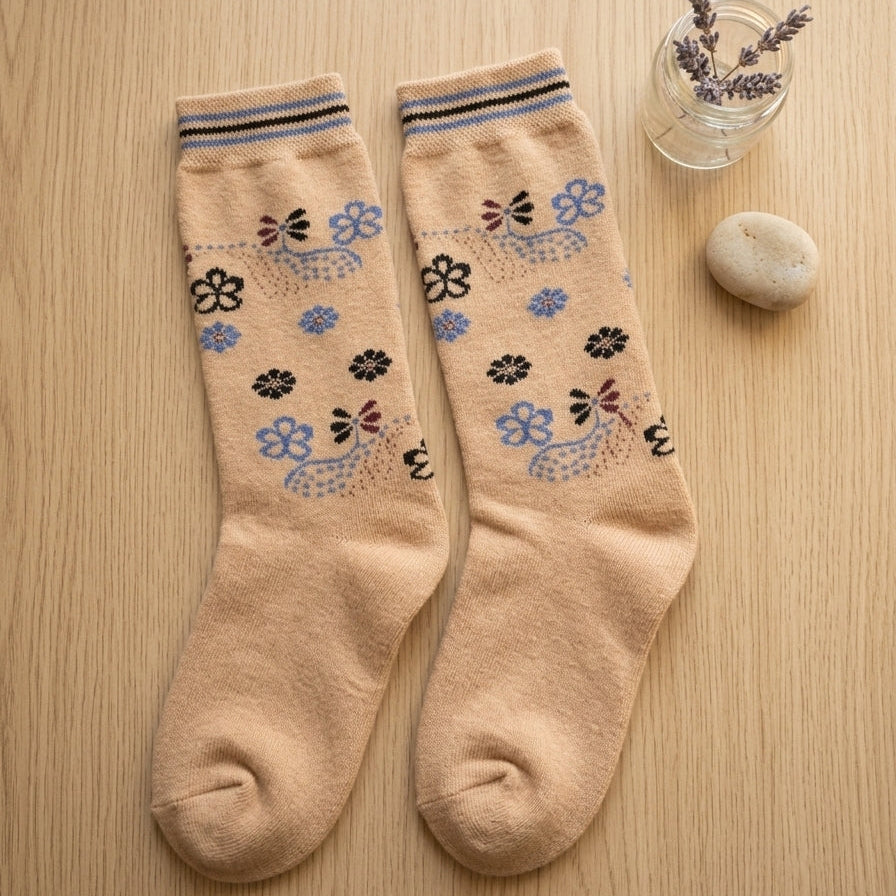 Aesthetic overhead flatlay view of the Range Studio apricot-pink whimsical kitty sherpa-lined rabbit wool socks laid flat on a light wooden floor next to a glass vase.