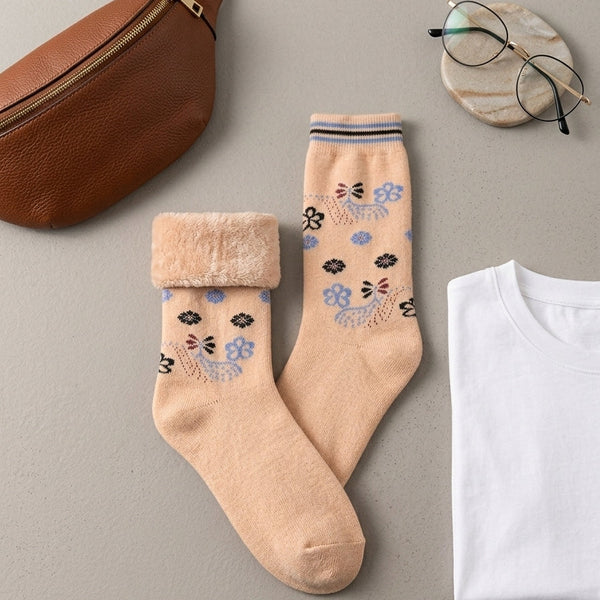 Aesthetic overhead flatlay view of the Range Studio apricot-pink floral sherpa-lined rabbit wool socks styled next to a brown leather bag, clear glasses, and a white t-shirt.